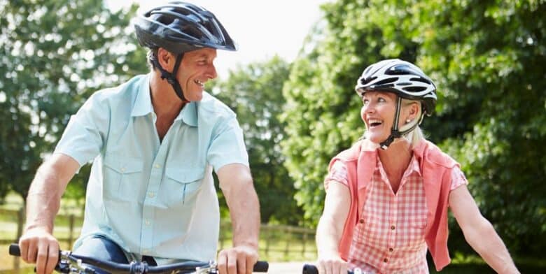 middle-aged couple looking at each other and smiling while riding bikes in the countryside