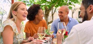 A group of friends enjoying an outdoor meal with white wine