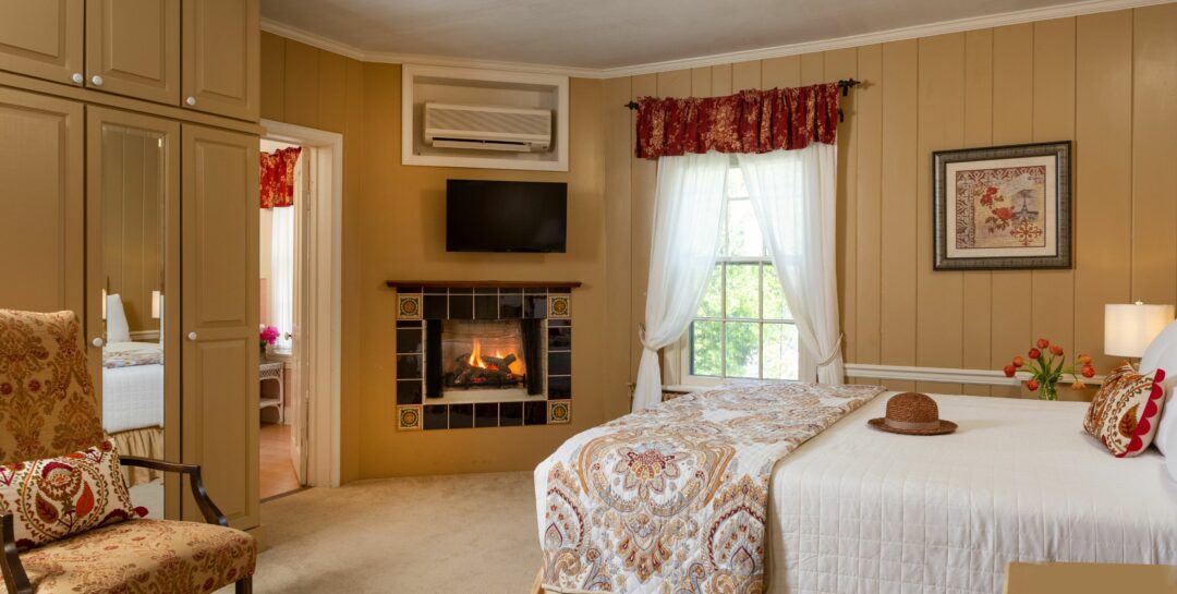 Paneled guest room with warm tones, carpeting and hardwood, corner fireplace, and storage.
