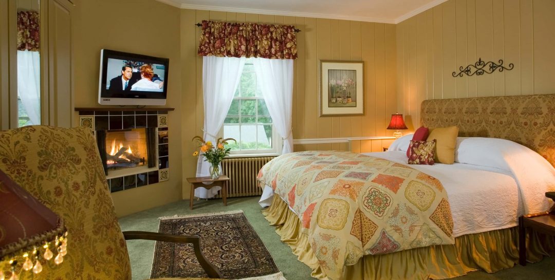 King bed in a room with warm earth-toned walls and a fireplace