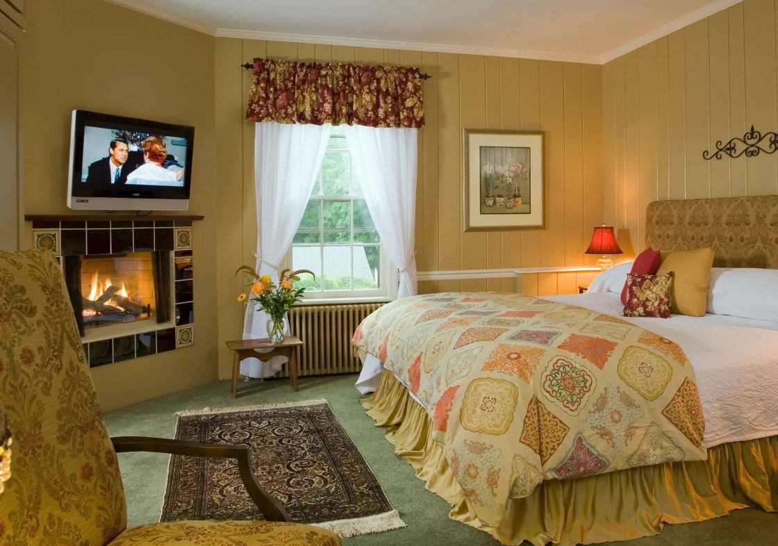 King bed in a room with warm earth-toned walls and a fireplace