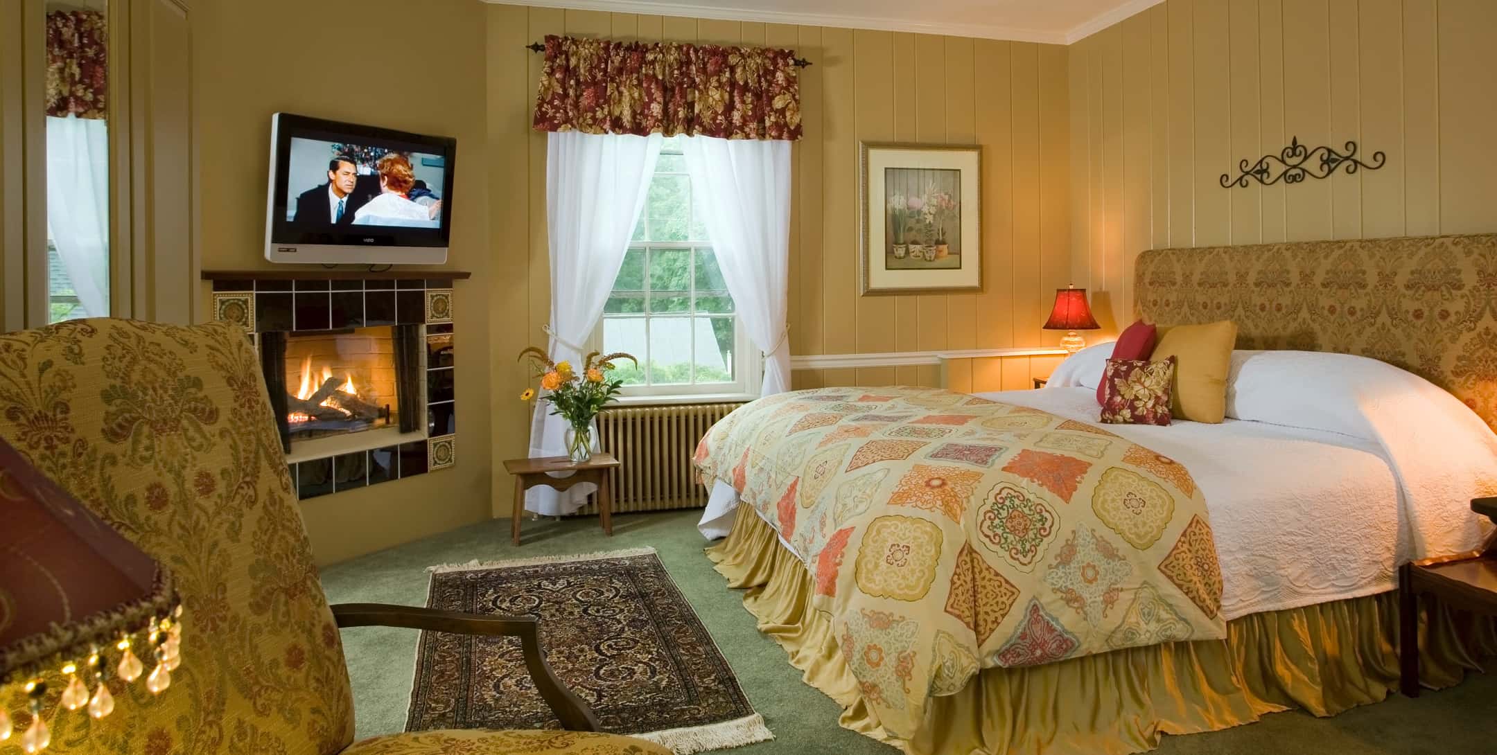 King bed in a room with warm earth-toned walls and a fireplace