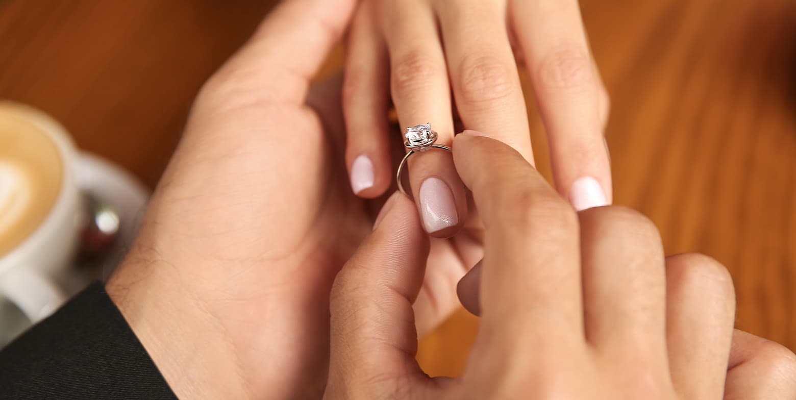 Man putting engagement ring on woman's finger