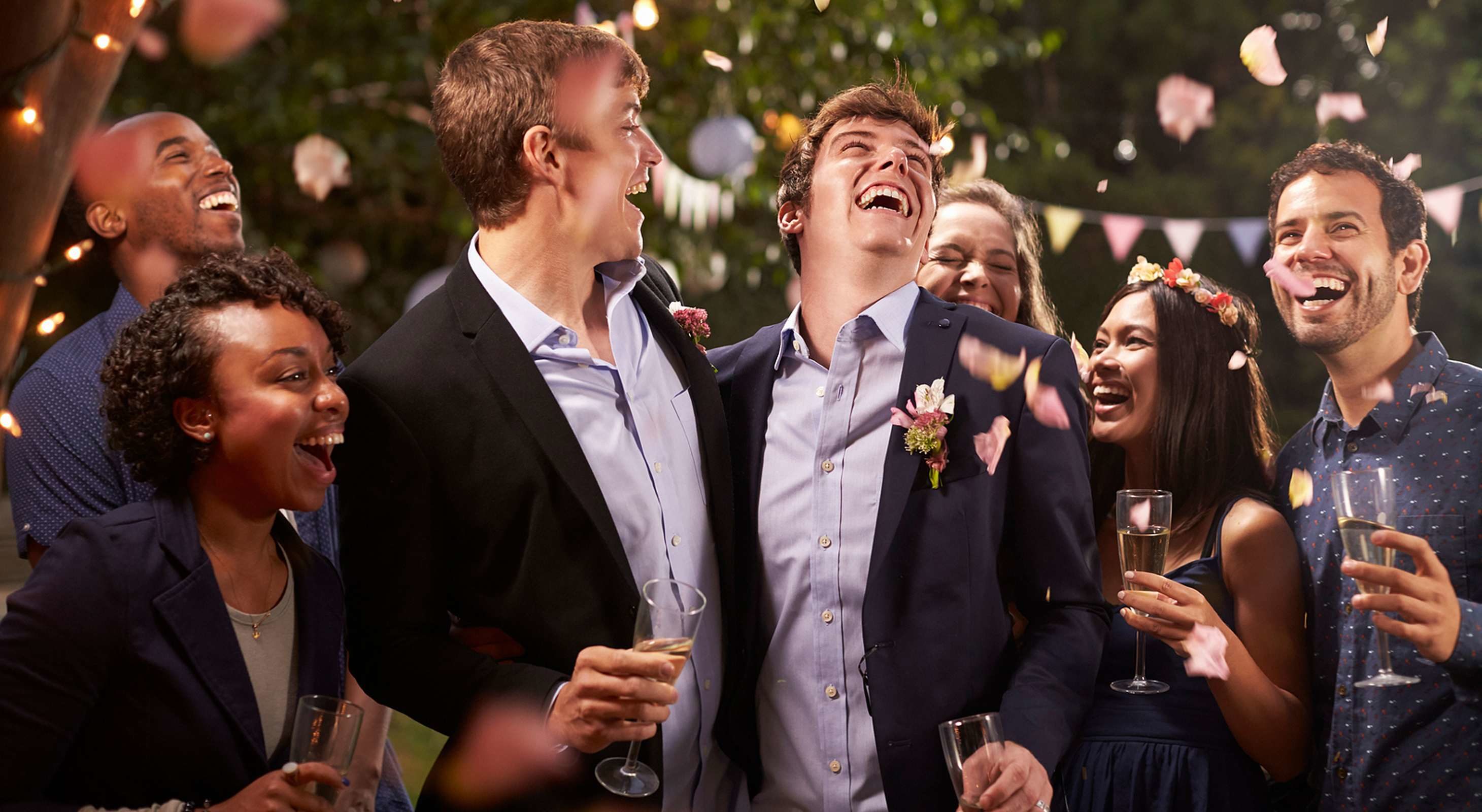 two grooms surrounded by friends at their wedding