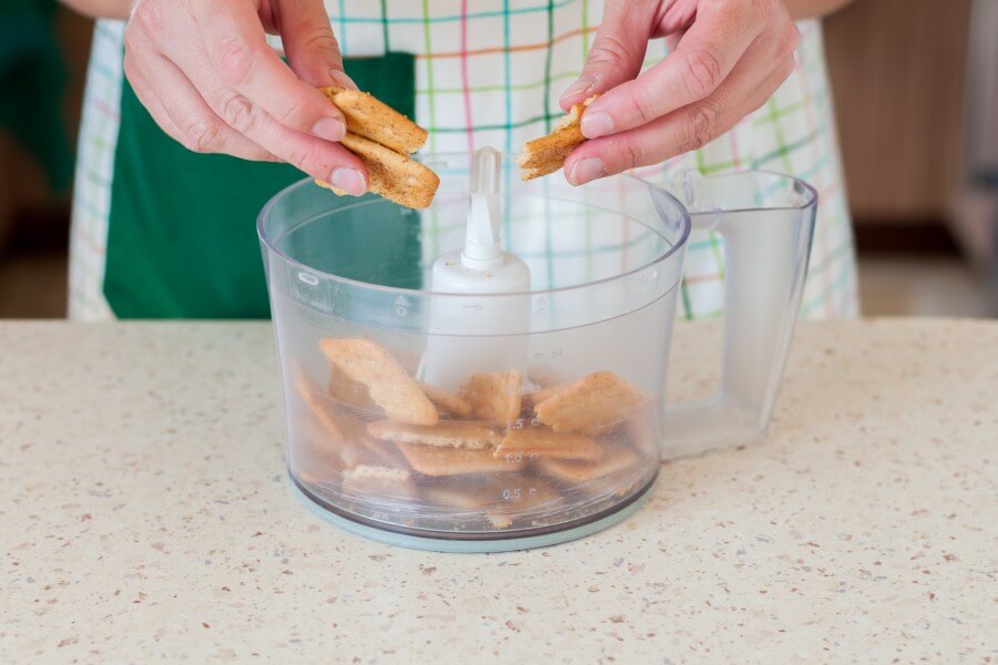 woman breaking up graham crackers while baking