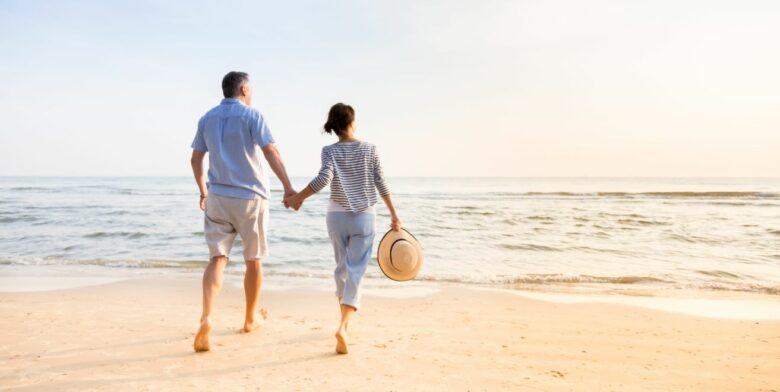 A couple is walking hand in hand at the beach
