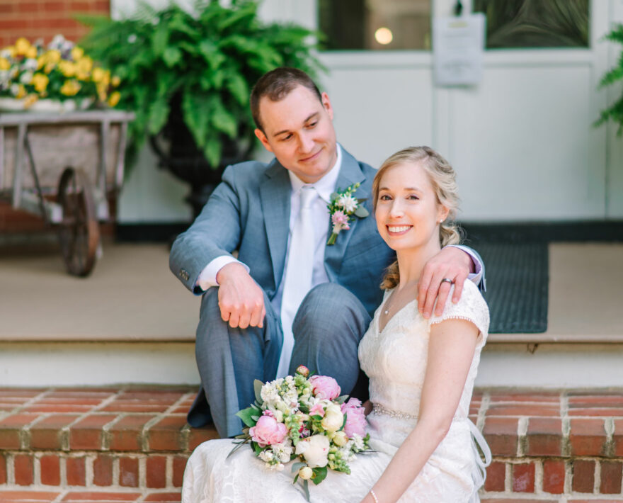 Bride and groom sitting on brick steps with front door behind them