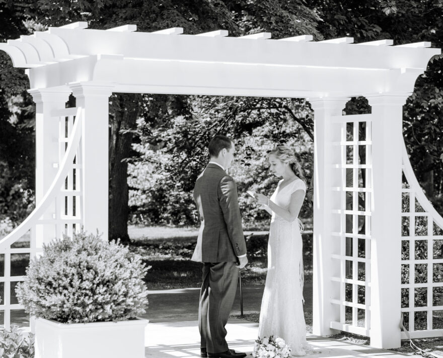 Couple exchanging vows under pergola, a black and white photograph