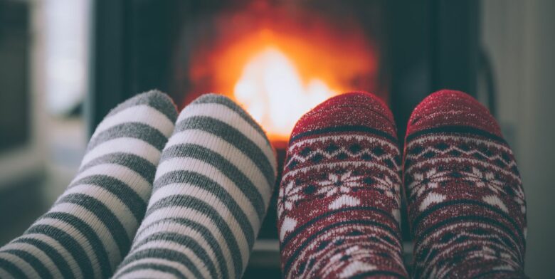 A couple has their socked feet in front of a fire