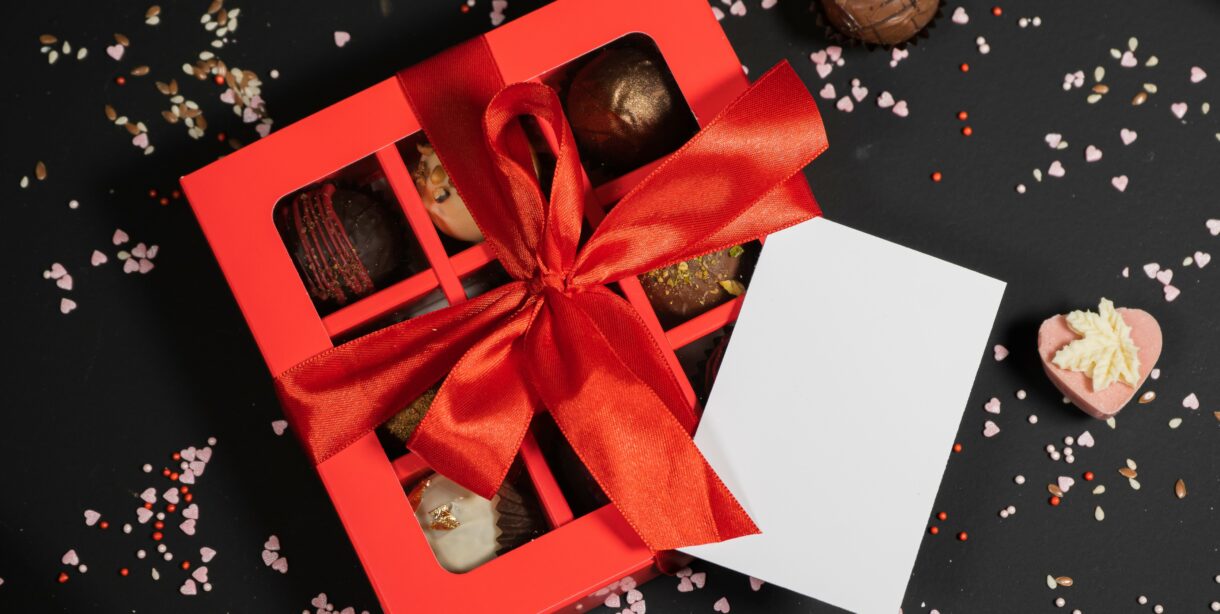 Handmade chocolate truffle candies in a red box on a dark background.