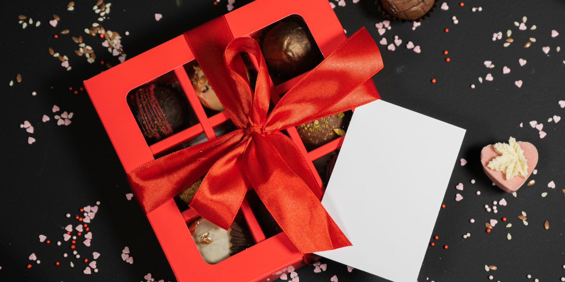 Handmade chocolate truffle candies in a red box on a dark background.