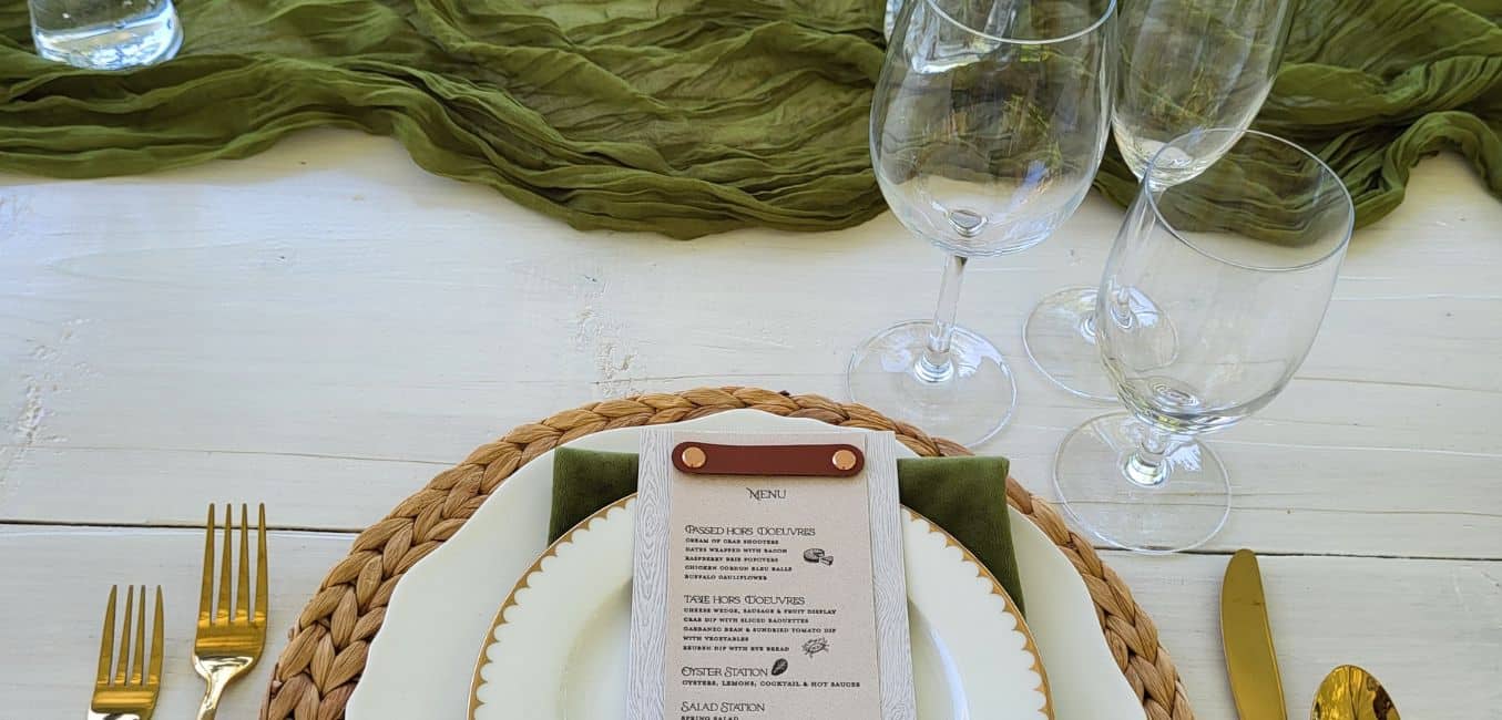 white table with green scarf draped as centerpiece and table setting with crystal and cutlery