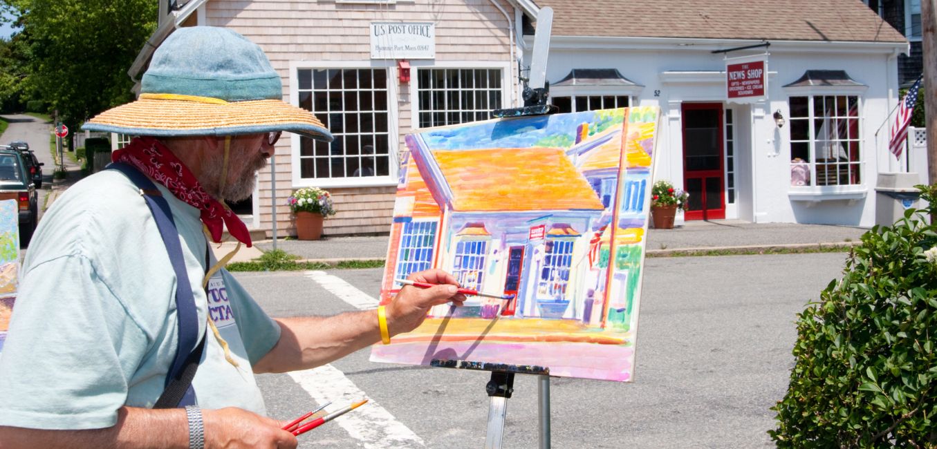 an artist plein air painting a village street and buildings 