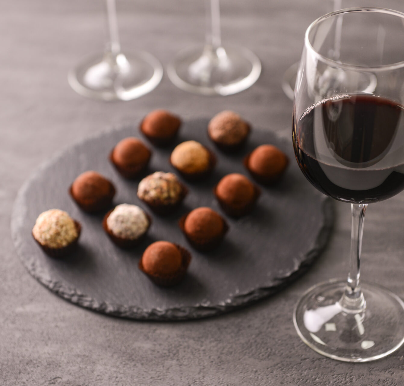 Red wine with chocolate truffles on grey background