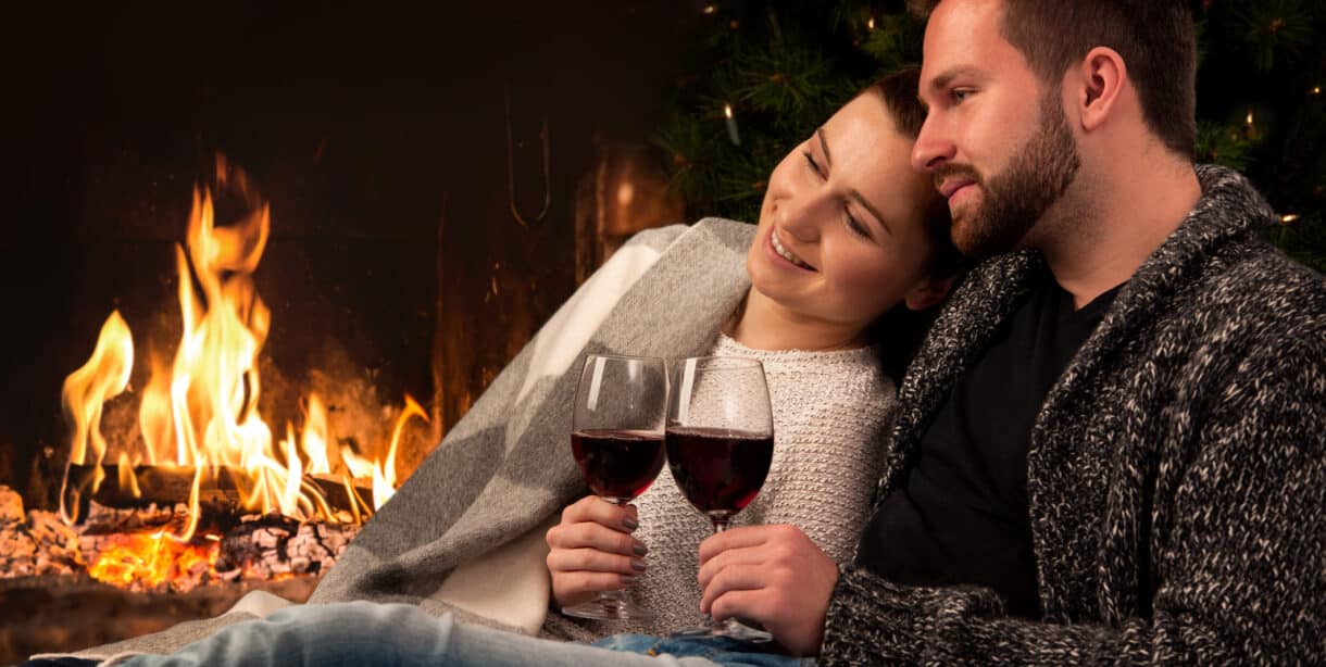 Couple with glass of wine at fireplace