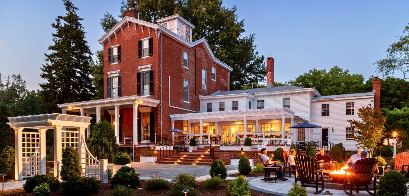 exterior of brampton inn at dusk with guests at fire pit