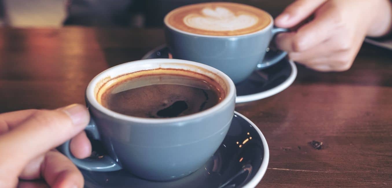 closeup of mugs of specialty coffee that a couple is sharing at a cafe