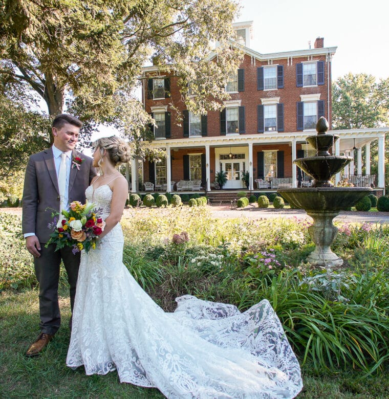 Bride and Groom in front of the fountain outside Brampton 1860 front facade